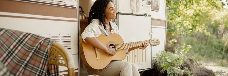 Happy woman with a guitar in her caravan | Financial Information | Tiger Finance